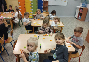 Dzieci przy stolikach wyklejają bibułą pterodaktyle.