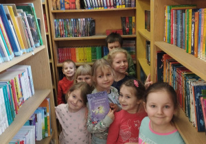 Dzieci stoją przy półkach z książkami.