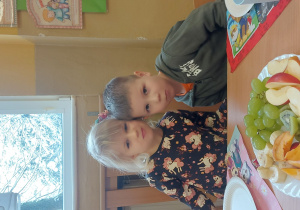chłopiec i dziewczynka siedzą przy stole i przytulają się główkami pozując do zdjęcia