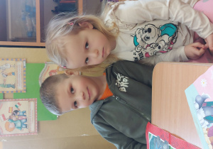 chłopiec i dziewczynka siedzą przy stole i przytulają się główkami pozując do zdjęcia