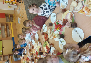 Wszystkie dzieci siedzą wspólnie przy stole i jedzą śniadanie