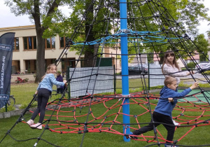 Dzieci wspinają się po pajęczynie na placu zabaw.