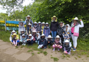 Grupa dzieci z Paniami w kapeluszach pszczelarskich.
