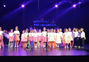 Dzieci śpiewają piosenkę na scenie.