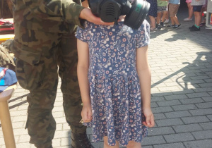 Dziewczynka przymierza wojskową maskę tlenową