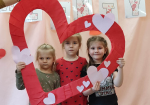 Trzy dziewczynki trzymają serce i pozują do zdjęcia.