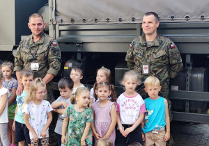 Dwóch żołnierzy wraz z dziećmi pozują do zdjęcia.
