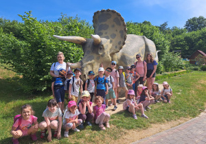 Grupa dzieci pozuje do zdjęcia przy Triceratopsie.