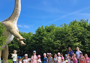 Grupa dzieci pozuje do zdjęcia przy Brachiozaurze.