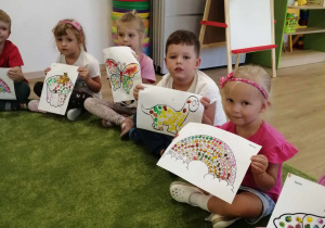Dzieci pokazują obrazki malowane farbą.