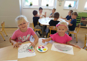 Dziewczynki malują palcami umoczonymi w farbie obrazki z kropek.