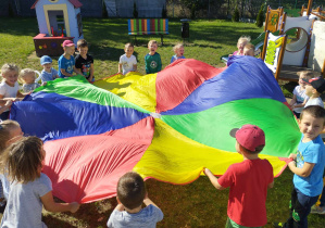 Dzieci podczas zabawy z kolorową chustą animacyjną.