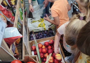 Dzieci oglądają i kupują owoce w sklepie spożywczym.