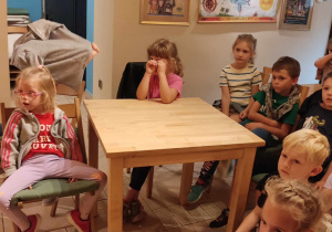 Grupa dzieci siedzi przy stolikach w kawiarence.