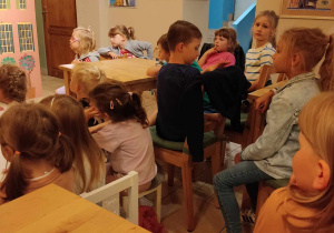 Grupa dzieci siedzi przy stolikach w kawiarence.