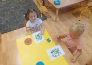 Dzieci stemplują palcem umoczonym w farbie szablon żaby