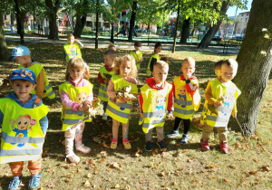 Dzieci stojąc trzymają liście
