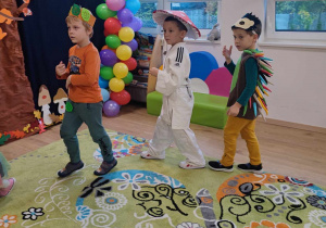 Dzieci w jesiennych strojach tańczą podczas balu.