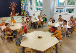 Dzieci siedzą przy stoliku podczas słodkiego poczęstunku.