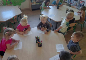 Dzieci przy stolikach kolorują malowanki