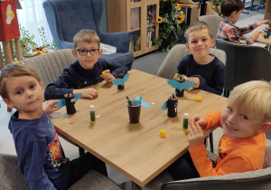 Chłopcy siedzą przy stolikach i dekorują nietoperze.