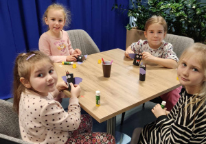 Dziewczynki siedzą przy stolikach i dekorują nietoperze.