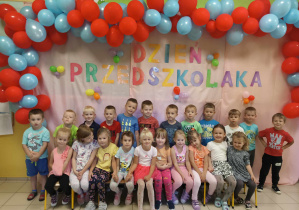 dzieci pozują do zdjęcia grupowego na tle napisu Dzień Przedszkolaka