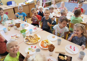 Dzieci jedzą wspólnie słodki poczęstunek