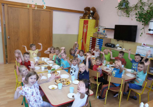 Dzieci jedzą wspólnie słodki poczęstunek