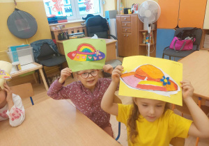 Dzieci trzymają nad głowami swoje prace plastyczne.