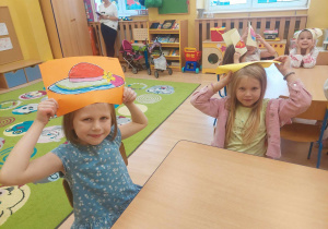 Dzieci trzymają nad głowami swoje prace plastyczne.