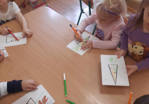 Dzieci kolorują obrazek przedstawiający marchewkę.