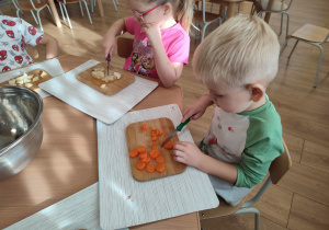 Chłopiec krojący marchewkę