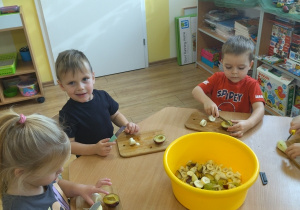 Dzieci krojące na małych deskach owoce