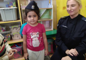 Dziewczynka stoi w czapce policjanta