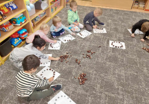 Dzieci układają koło z kasztanów na dywanie