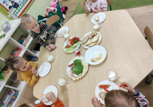 Dzieci jedzą śniadanie przy stolikach
