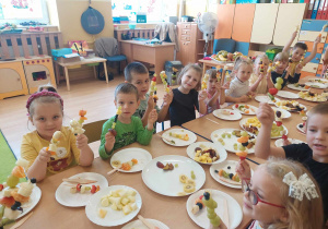 Dzieci pokazują przygotowane z owoców szaszłyki.