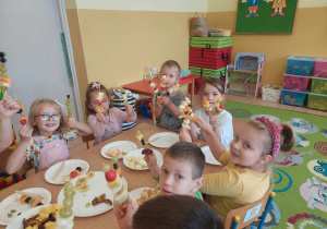Dzieci pokazują przygotowane z owoców szaszłyki.