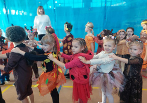 Przebrane dzieci w jesienne stroje tańczą w rytm muzyki.