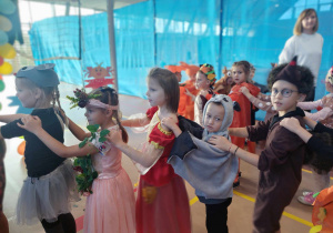 Przebrane dzieci w jesienne stroje tańczą w rytm muzyki.