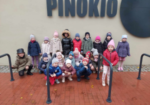 Grupowe zdjęcie dzieci przed teatrem Pinokio w Łodzi.
