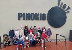 Grupowe zdjęcie dzieci przed teatrem Pinokio w Łodzi.