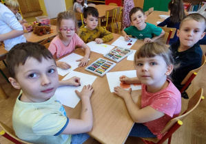 Dzieci pastelami olejnymi na białej kartce malują misia.