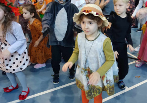 Dziewczynka w kapeluszu tańczy w rytm muzyki.