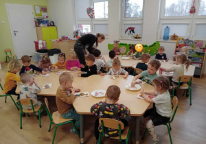 Dzieci przy stolikach dekorują ciastka