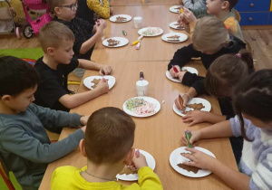 dzieci dekorują pierniki lukrem i czekoladą