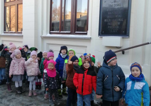 Dzieci stoją ustawieni w pary przed Miejskim Domem Kultury.
