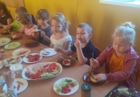 Dzieci siedzą przy stoliku na którym znajdują się artykuły spożywcze