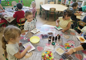 Dzieci siedzą przy stoliku podczas warsztatów mydlarskich.